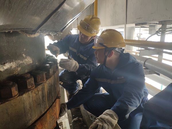 4月6日，機械修造部檢修二部張振華、盧超逸在檢修平臺處，進(jìn)行4號氣化爐破渣機下降管短節(jié)法蘭螺栓的拆卸工作。.jpg
