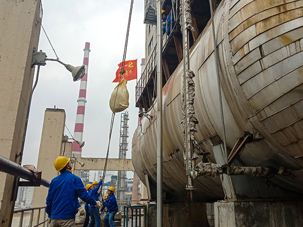 5月10日中午，在動力車間三期工藝除氧器地面，黨員突擊隊隊員用滑輪往工藝除氧器平臺運送鋼絲網(wǎng)，用以纏繞新填料.jpg