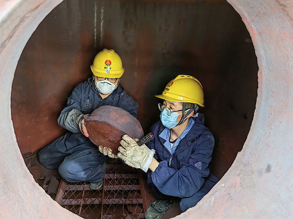 5月11日，動力車間三期工藝除氧器內部，黨員突擊隊隊員劉瑞斌和李震正在清理舊填料.jpg