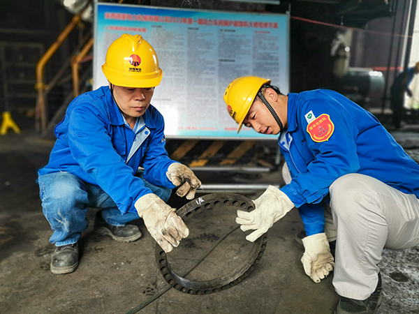 圖三：12日下午14時(shí)，在一期磨煤機(jī)廠房，陜西省技術(shù)能手姬霄給青工張跟潮講解磨煤機(jī)搖臂曲拐內(nèi)環(huán)及動(dòng)作原理。.jpg